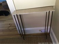 Granite foyer table with beige granite top and metal legs, placed against a wall.