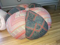 Side view of patchwork floor pouf showing red, cream, and dark blue geometric patterns