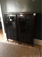 Front view of the vintage dark wood china cabinet with two glass doors featuring arched muntins.