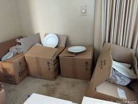 Four cardboard boxes filled with white/ivory dinner plates and soup bowls, some plates shown on top of boxes.