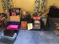 Wide view showing lot items including calculator, paper cutter, organizers, rulers, lamp, and books on carpet floor.
