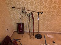 Full view of five items: three decorative swords, one curved sword with scabbard, and a microphone stand.