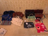 All bags displayed on floor against wallpaper, showing size and variety of duffel bags, purses, and wallets.