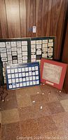 Photo showing three framed collections of wine labels including The Great Wines of Bordeaux and Burgundy, Mouton Rothschild labels from 1945 to 1981, and a framed map labeled Vins De France. Frames show minor wear, one has a crack in the glass.