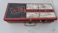 Closed red metal carrying case with WEN branding and 'Soldering Gun Home Utility Kit' label.