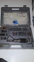 Open gray molded plastic case showing ratchet screwdriver handle, multiple screwdriver bits, extensions, and bit holders arranged in molded slots.