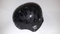 Side and top view of a black Krash branded safety helmet with reflective geometric pattern and logo.