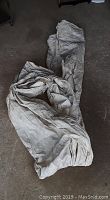 Off-white heavy canvas painter's tarp with creases and folds laid out on floor for display.