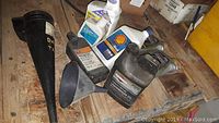 Assortment of motor oil plastic bottles and black funnels on wooden surface