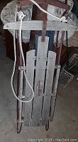 Image showing full top view of the sled, highlighting the weathered wooden slats and red metal frame with attached pull rope.