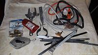 Photo showing various hand tools and accessories arranged, including pipe wrench, saw blades, tape measure, cables, and connectors.