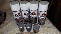 Four cans of Kilz Complete spray primer paint with white caps and brown labels