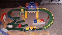 Full view of Geotrax train layout with mixed track pieces, train cars on track, and accessories including buildings and fences