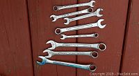 Photo showing 8 forged steel combination wrenches with metric sizes, some marked OEM, arranged on wooden surface.