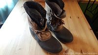 Pair of men's size 12 Sorel winter boots on a wooden table showing front and side angles.