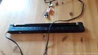 16 inch blacklight tube fixture placed on wooden surface, showing the entire fixture including power cord and plug.