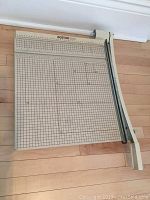 Top view of the paper cutter showing grid surface, measurement scales, and cutting arm.