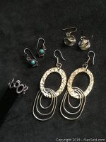 Group photo of collection showing all earrings and ring on black background