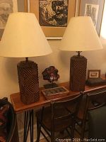 Pair of mid-century modern lamps with cinnamon geometric ceramic bases and cream fabric shades on wooden console table.