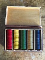 Top view of the open original wooden box showing five compartments with red, yellow, green, butterscotch, and navy Bakelite poker chips neatly stacked.