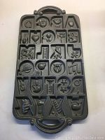 Full view of the heavy cast iron cookie mold showing all alphabet letters with decorative reliefs
