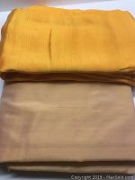 Two folded pieces of silk fabric stacked: dark melon colored fabric on top with subtle grid texture and a pale melon piece beneath with smooth texture and natural fiber variations.