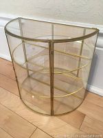 Curved glass display case showing semi-circular shape and gold frame on curved glass.