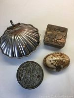 Four vintage-style trinket containers on a flat surface showing top and side views for identification.