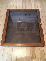 Top view of the wooden display case with plexiglass window showing reflection and wooden frame.