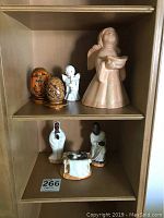 Shelf with ceramic manger scene figures, two decorative eggs, and ceramic angel figurines.