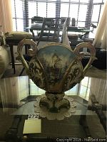 Front view of Capodimonte ceramic vase showing painted ship scene and ornate handles on glass table.