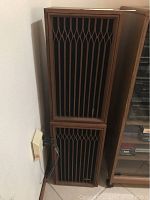 Two stacked vintage wooden speakers with distinct geometric grill design and cords visible on side.