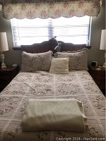 Front view of bed with floral quilt and pillows, showing headboard behind bed setup.