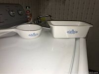 White Corning Ware saucepan and rectangular baking dish with blue cornflower pattern on white stove top