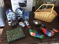 Overview photo showing Delft Blue ceramic houses, Dutch shoe figurines, elephant teapot, colorful wooden birds, a green trinket box, and a wicker basket.