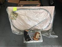 Wooden train table board 42x24 wrapped in plastic with coiled track track pieces on top, showing size and condition of table board and track