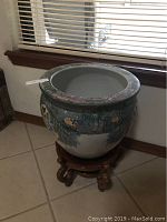 Full view of the large ceramic urn showing decorative exterior and open top interior.