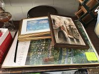 Four various sized framed prints including large Monet's Years at Giverny print in gold frame, a medium cityscape in carved wood frame, and smaller water themed prints stacked under them