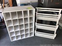 Photo shows white wood cubby organizer with 24 compartments next to white wood plate rack consisting of two shelves with horizontal slats.