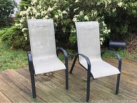 Two nylon mesh patio chairs on wood deck, black metal frames, light colored nylon seating and back.