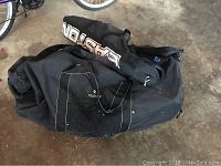 Black soft carry bags containing paintball gear and accessories, including helmet and shoes.