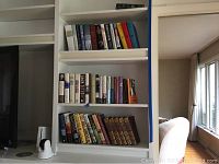 Bookshelf displaying a collection of modern novels and classic literature with colorful and brown spines, arranged on three shelves