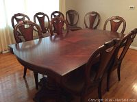 Ten chairs arranged around matching dining table on wood floor