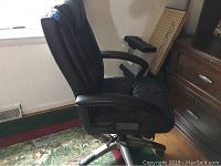 Front side view of black vinyl Stress Master desk chair with padded armrests and cushioned back showing overall condition and shape.