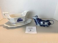 Gravy boat and cow creamer displayed side by side on a white surface with lot card