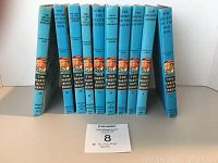 Front view of ten Hardy Boys books lined up showing blue spines with titles and volume numbers ranging from 3 to 48