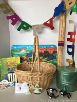 Photo shows oval wicker basket with handle, wooden rainstick, green tins, books, and Halloween decorations arranged under Happy Birthday banner.