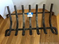 Front angled view of black metal fireplace log rack on hardwood floor