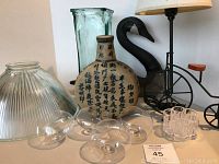 Photo showing decorative glass light fixture cover, plastic flower frog, floating candle holders, Asian style ceramic vase with script, green glass vase, and bicycle lamp with globe shade