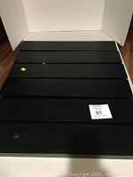 Top view of six black or dark espresso colored wall shelves stacked aligned showing surface condition and finish.